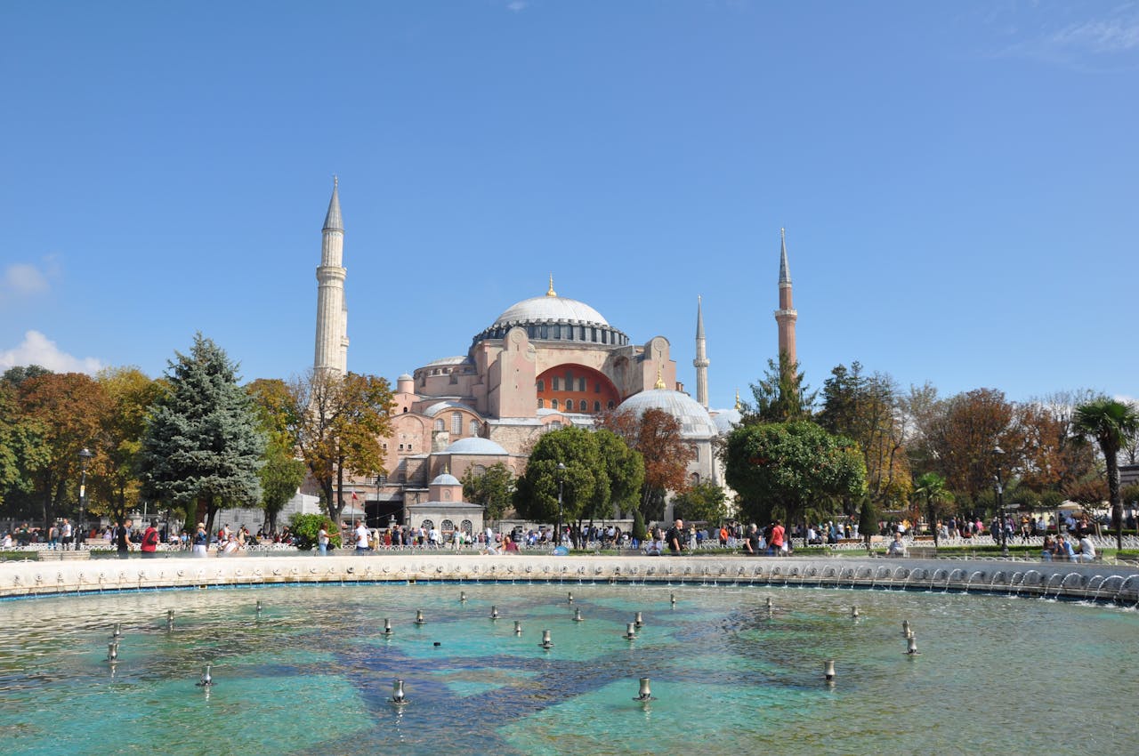 Stunning view of Hagia Sophia Grand Mosque with blue sky and fountain. Located in İstanbul, it's a historic and architectural gem.